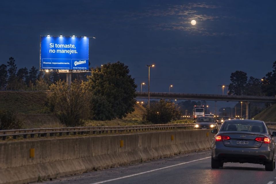 Cartel iluminado de noche con luna sobre una autopista